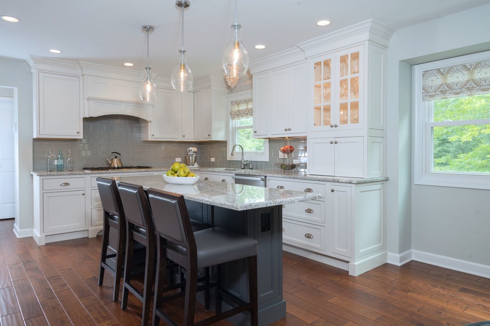 Large transitional u-shaped medium tone wood floor and brown floor eat-in kitchen photo in Philadelphia with an undermount sink, recessed-panel cabinets, white cabinets, granite countertops, gray backsplash, subway tile backsplash, stainless steel appliances and an island