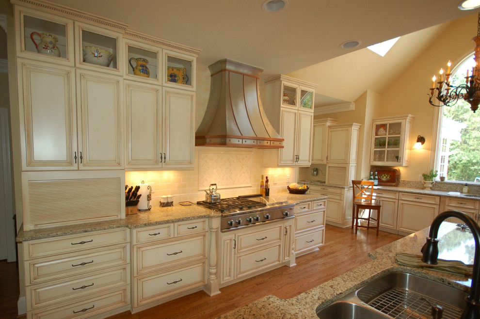 Klassisk inredning av ett avskilt, stort u-kök, med en dubbel diskho, luckor med upphöjd panel, vita skåp, granitbänkskiva, vitt stänkskydd, stänkskydd i tunnelbanekakel, mellanmörkt trägolv, en köksö och brunt golv