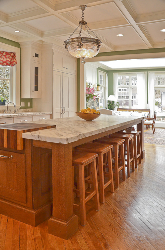 Bild på ett mellanstort lantligt kök, med en undermonterad diskho, luckor med infälld panel, vita skåp, bänkskiva i täljsten, flerfärgad stänkskydd, stänkskydd i sten, rostfria vitvaror, mörkt trägolv, en köksö och brunt golv