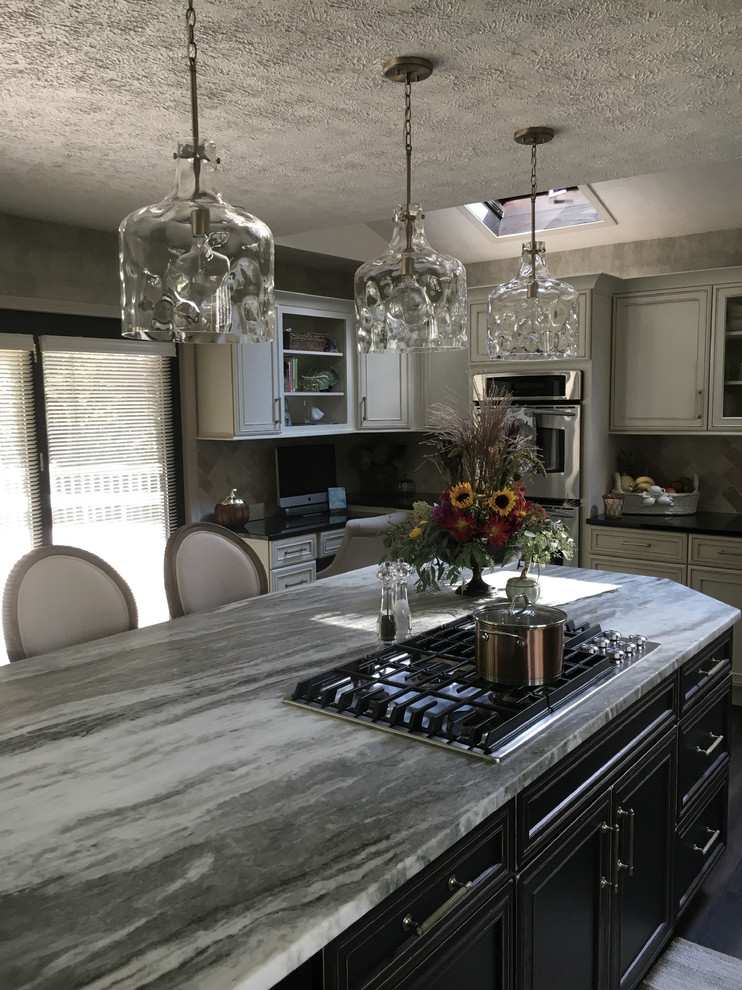 Large traditional u-shaped kitchen/diner in Other with a submerged sink, recessed-panel cabinets, white cabinets, granite worktops, white splashback, ceramic splashback, stainless steel appliances, laminate floors, an island, grey floors and black worktops.