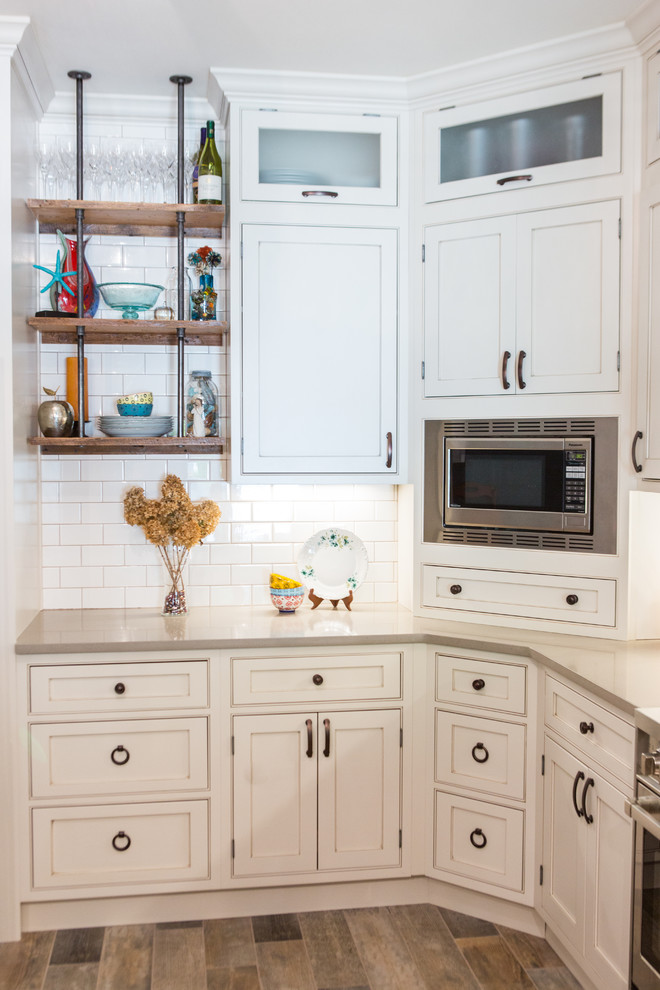 Foto på ett mellanstort lantligt kök, med en rustik diskho, luckor med profilerade fronter, vita skåp, bänkskiva i kvartsit, vitt stänkskydd, stänkskydd i tunnelbanekakel, rostfria vitvaror, klinkergolv i keramik och en halv köksö