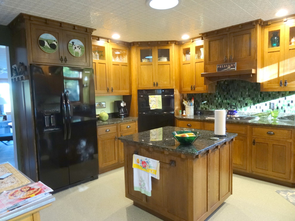 Inredning av ett amerikanskt avskilt, mellanstort u-kök, med en undermonterad diskho, släta luckor, skåp i mörkt trä, granitbänkskiva, grönt stänkskydd, stänkskydd i glaskakel, svarta vitvaror, linoleumgolv och en köksö