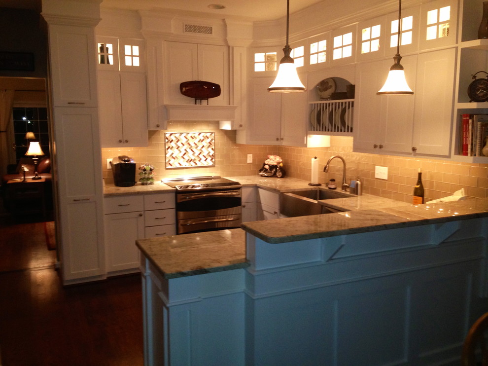 Photo of a traditional u-shaped kitchen/diner in Baltimore with a belfast sink, shaker cabinets, white cabinets, granite worktops, beige splashback, glass tiled splashback and stainless steel appliances.