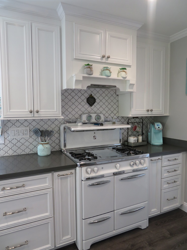 Small farmhouse galley vinyl floor and brown floor open concept kitchen photo in Los Angeles with an undermount sink, recessed-panel cabinets, white cabinets, quartzite countertops, white backsplash, ceramic backsplash, stainless steel appliances, a peninsula and gray countertops