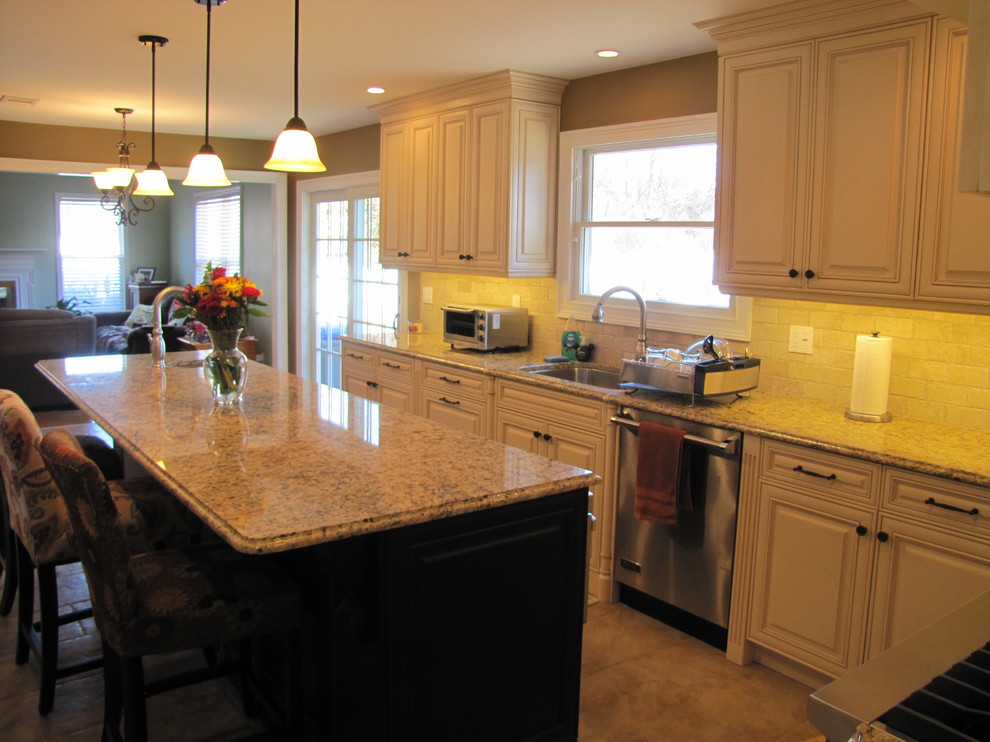 Example of a classic l-shaped eat-in kitchen design in New York with an undermount sink, raised-panel cabinets, white cabinets, granite countertops, beige backsplash, subway tile backsplash and stainless steel appliances