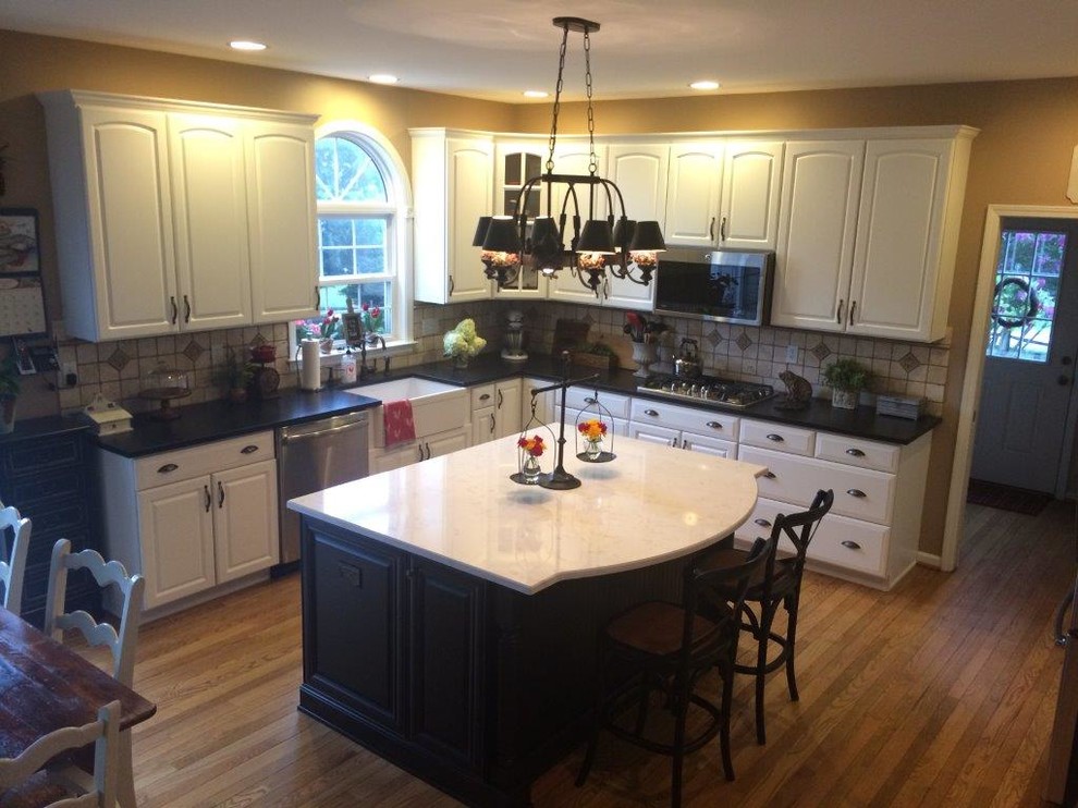 Exempel på ett mellanstort klassiskt kök och matrum, med en rustik diskho, svarta skåp, bänkskiva i kvartsit, beige stänkskydd, rostfria vitvaror och en köksö