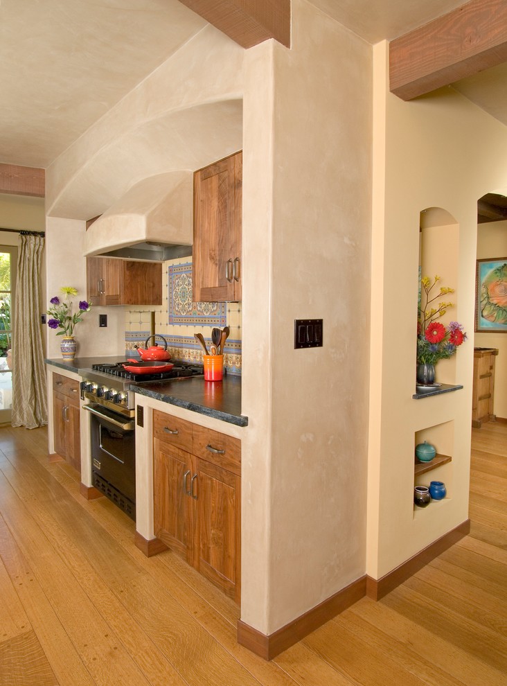 サンフランシスコにある地中海スタイルのおしゃれなキッチン (シェーカースタイル扉のキャビネット、中間色木目調キャビネット、マルチカラーのキッチンパネル、黒い調理設備、無垢フローリング) の写真