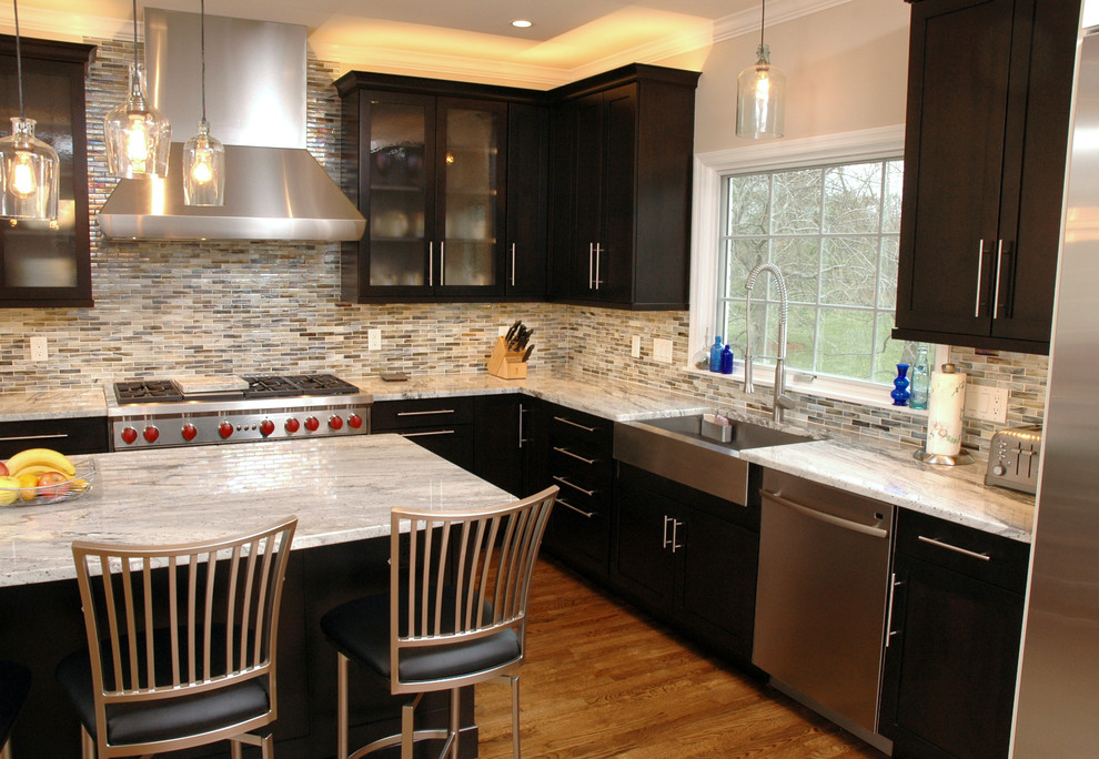 Foto på ett funkis kök, med en undermonterad diskho, luckor med infälld panel, skåp i mörkt trä, flerfärgad stänkskydd och rostfria vitvaror