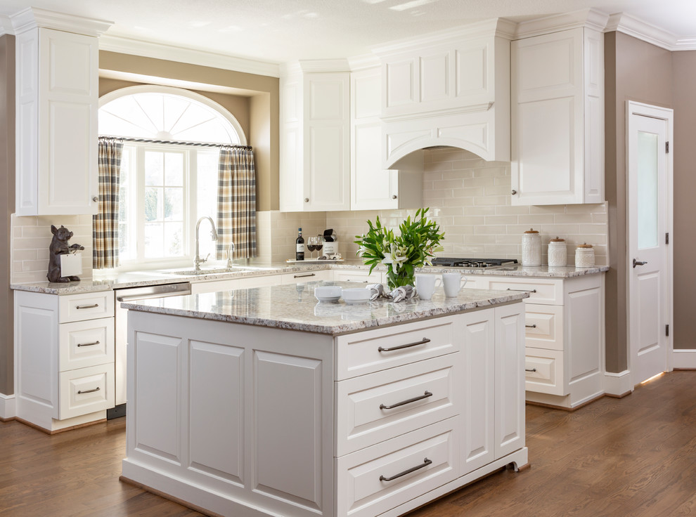 Example of a large transitional l-shaped medium tone wood floor and brown floor eat-in kitchen design in Kansas City with an undermount sink, raised-panel cabinets, white cabinets, quartzite countertops, beige backsplash, subway tile backsplash, stainless steel appliances, an island and multicolored countertops