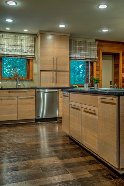 Example of a mid-sized trendy l-shaped medium tone wood floor open concept kitchen design in DC Metro with a single-bowl sink, flat-panel cabinets, light wood cabinets, granite countertops, beige backsplash, glass tile backsplash, paneled appliances and an island