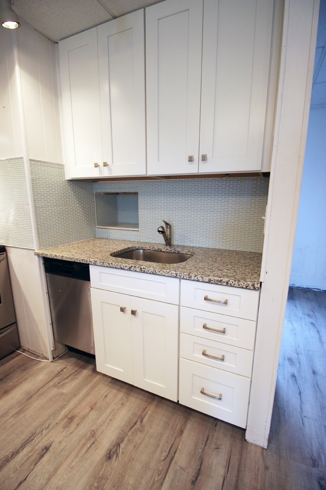 This is an example of a small contemporary l-shaped kitchen/diner in Wilmington with a submerged sink, shaker cabinets, white cabinets, granite worktops, green splashback, glass tiled splashback, stainless steel appliances and an island.