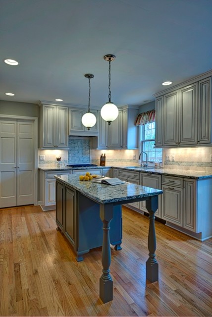 Mid-sized trendy l-shaped medium tone wood floor eat-in kitchen photo in DC Metro with an undermount sink, raised-panel cabinets, white cabinets, quartz countertops, multicolored backsplash, mosaic tile backsplash, stainless steel appliances and an island