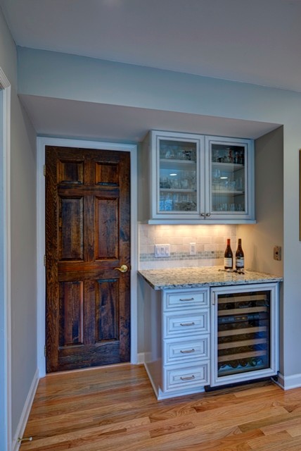 Inspiration for a mid-sized contemporary l-shaped medium tone wood floor home bar remodel in DC Metro with an undermount sink, raised-panel cabinets, white cabinets, quartz countertops, multicolored backsplash and mosaic tile backsplash