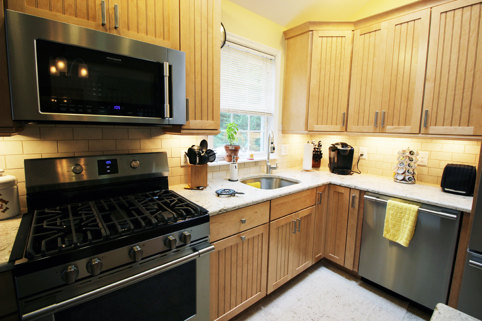 Foto di una cucina tradizionale di medie dimensioni con lavello sottopiano, ante in legno chiaro, top in quarzite, paraspruzzi beige, elettrodomestici in acciaio inossidabile e pavimento con piastrelle in ceramica