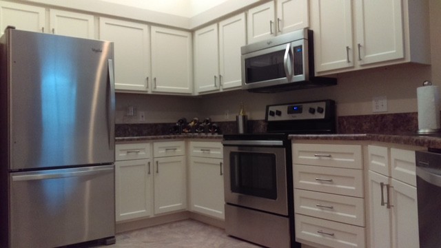 Imagen de cocina actual de tamaño medio con puertas de armario blancas y electrodomésticos de acero inoxidable