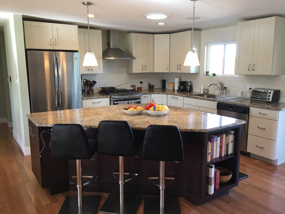 Example of a classic l-shaped light wood floor and brown floor eat-in kitchen design in Denver with recessed-panel cabinets, white cabinets, granite countertops, white backsplash, ceramic backsplash, stainless steel appliances, an island and a double-bowl sink