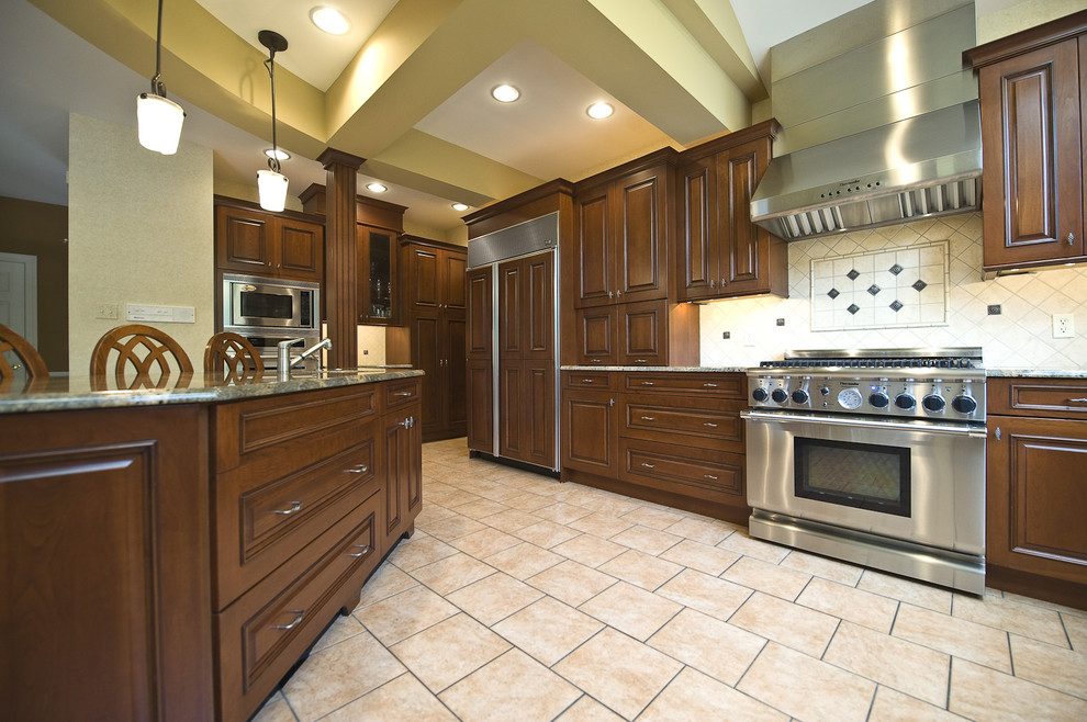 Example of a classic kitchen design in Philadelphia with raised-panel cabinets, medium tone wood cabinets, beige backsplash and stainless steel appliances