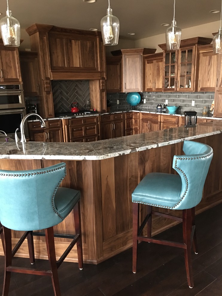 Inspiration for a large transitional u-shaped dark wood floor and brown floor eat-in kitchen remodel in Omaha with shaker cabinets, medium tone wood cabinets, granite countertops, gray backsplash, stone tile backsplash, stainless steel appliances and a peninsula