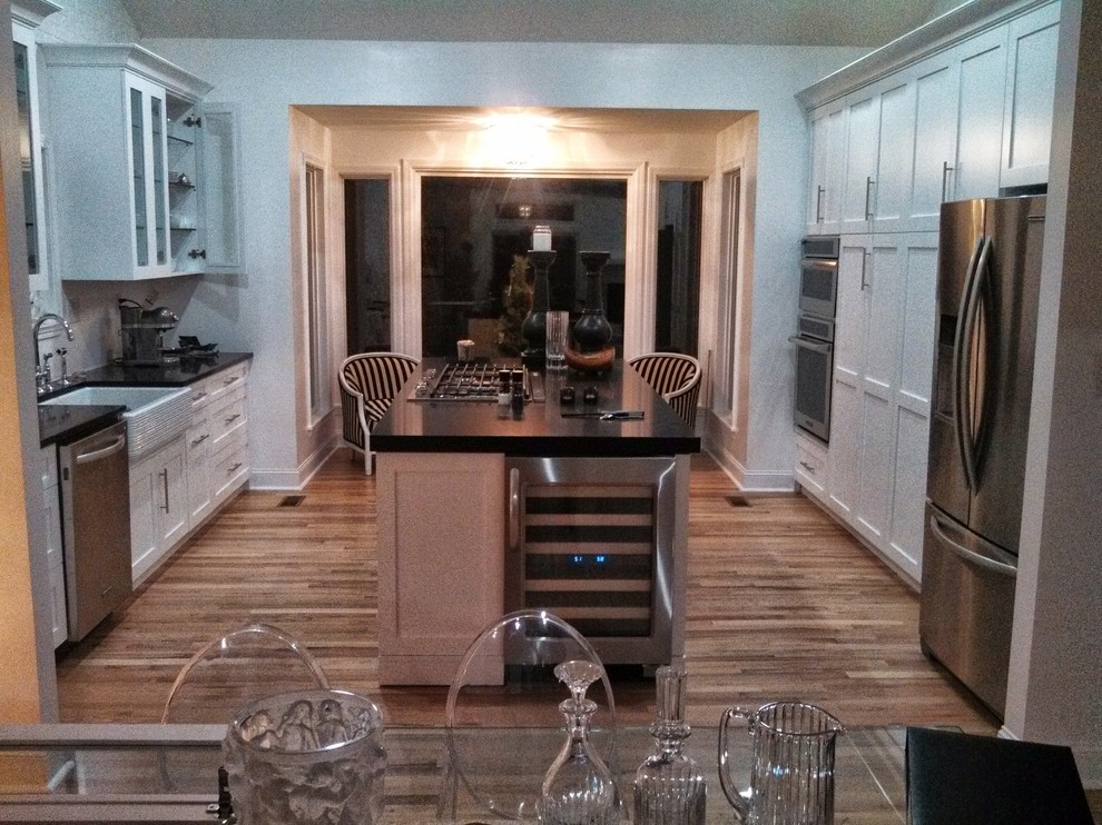 アトランタにある高級な中くらいなトランジショナルスタイルのおしゃれなキッチン (エプロンフロントシンク、ガラス扉のキャビネット、白いキャビネット、オニキスカウンター、シルバーの調理設備、淡色無垢フローリング) の写真