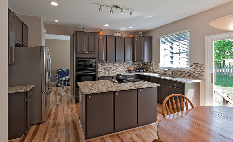 Exempel på ett mellanstort klassiskt kök och matrum, med en undermonterad diskho, luckor med upphöjd panel, bruna skåp, granitbänkskiva, vitt stänkskydd, stänkskydd i glaskakel, svarta vitvaror och ljust trägolv