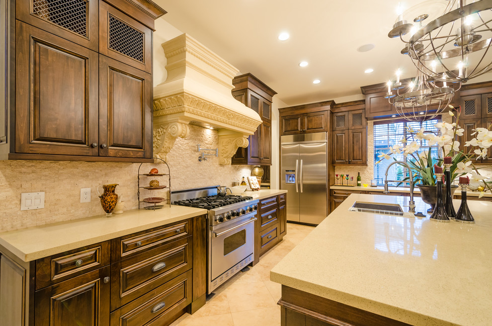 Exempel på ett mellanstort klassiskt beige beige kök, med en undermonterad diskho, luckor med upphöjd panel, skåp i mörkt trä, rostfria vitvaror, en köksö, beiget golv, granitbänkskiva, beige stänkskydd och stänkskydd i stenkakel