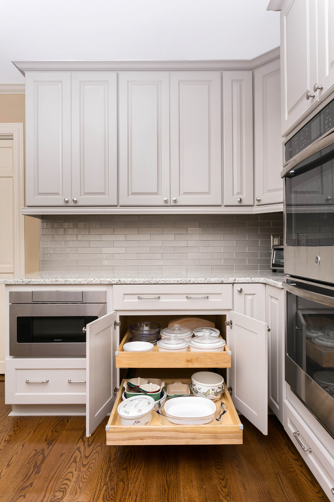Example of a mid-sized classic u-shaped light wood floor eat-in kitchen design in Charleston with an undermount sink, raised-panel cabinets, gray cabinets, wood countertops, gray backsplash, subway tile backsplash, stainless steel appliances and a peninsula
