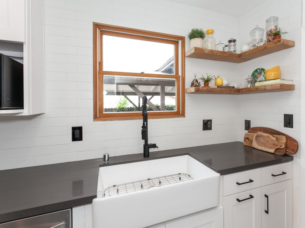 Foto på ett mellanstort funkis grå kök, med en rustik diskho, luckor med glaspanel, vita skåp, bänkskiva i kvarts, vitt stänkskydd, stänkskydd i glaskakel, svarta vitvaror, klinkergolv i keramik, en halv köksö och vitt golv