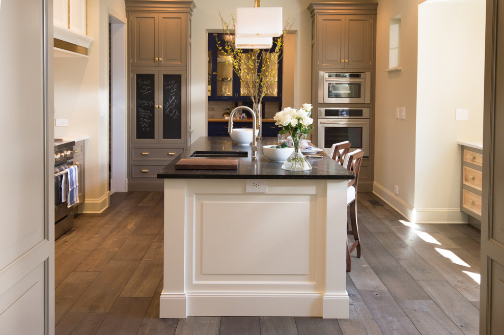 Inspiration for a large timeless galley medium tone wood floor open concept kitchen remodel in Chicago with an undermount sink, recessed-panel cabinets, white cabinets, onyx countertops, stainless steel appliances and an island