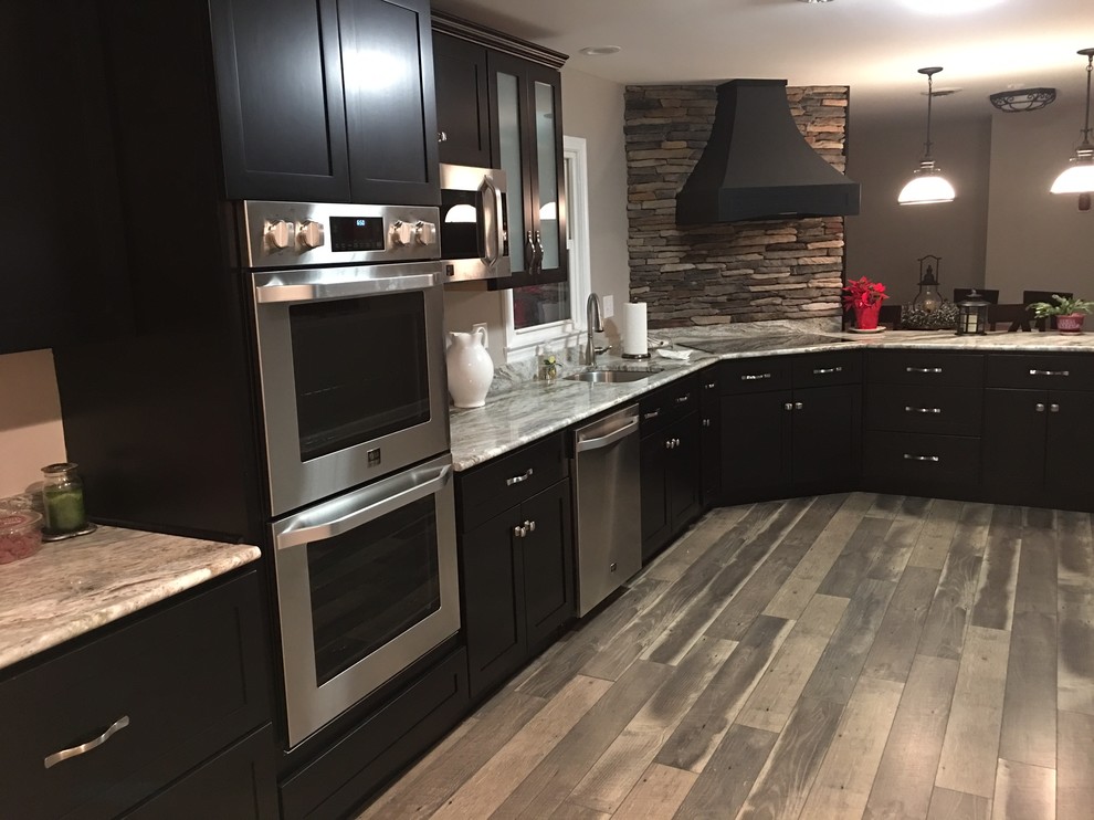 Exempel på ett avskilt, mellanstort klassiskt l-kök, med en undermonterad diskho, skåp i shakerstil, svarta skåp, marmorbänkskiva, brunt stänkskydd, rostfria vitvaror, mellanmörkt trägolv, en halv köksö och stänkskydd i stenkakel