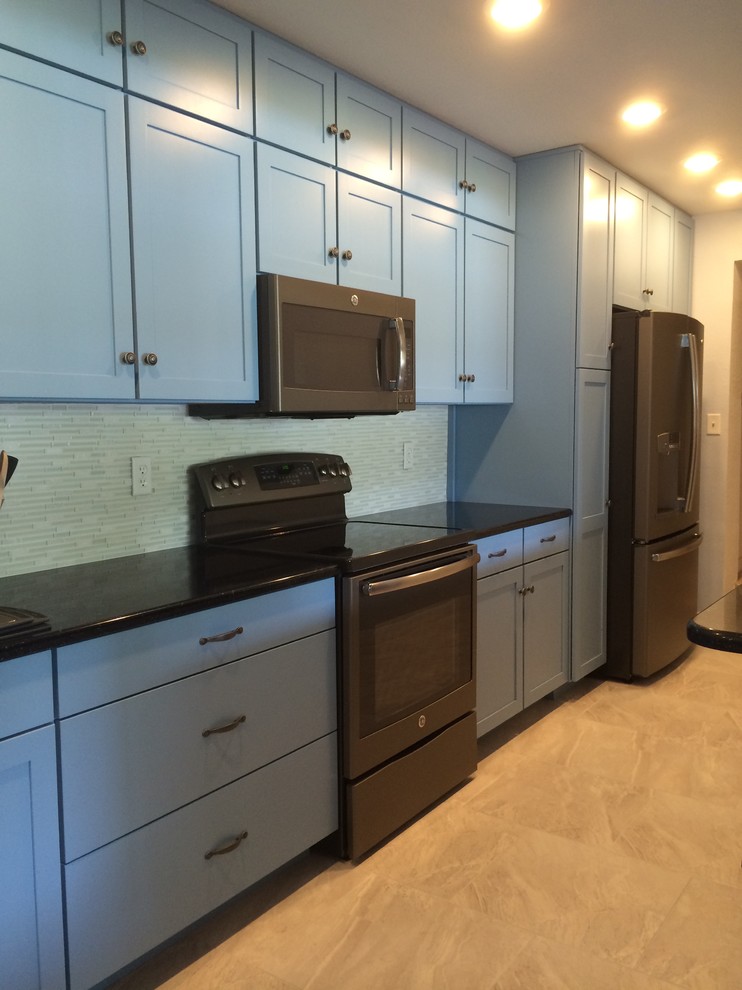 Example of a mid-sized tuscan single-wall ceramic tile enclosed kitchen design in Tampa with a double-bowl sink, flat-panel cabinets, blue cabinets, quartz countertops, gray backsplash, glass tile backsplash and no island