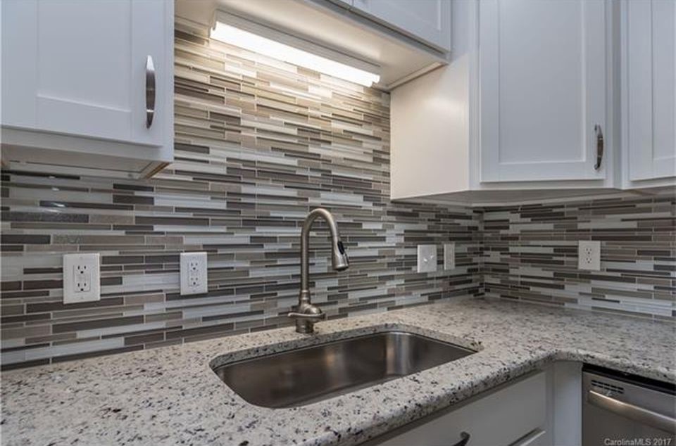 This is an example of a small contemporary l-shaped kitchen in Charlotte with a single-bowl sink, shaker cabinets, white cabinets, granite worktops, stainless steel appliances, porcelain flooring and grey floors.