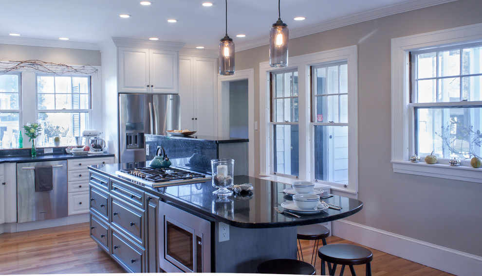 Eat-in kitchen - traditional l-shaped eat-in kitchen idea in Manchester with an undermount sink, raised-panel cabinets, white cabinets, granite countertops, gray backsplash and stainless steel appliances