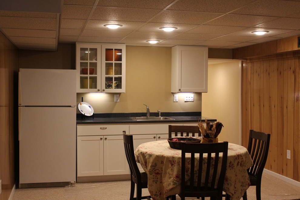 Mid-sized transitional single-wall carpeted eat-in kitchen photo in Other with an undermount sink, shaker cabinets, white cabinets, solid surface countertops, white appliances and no island