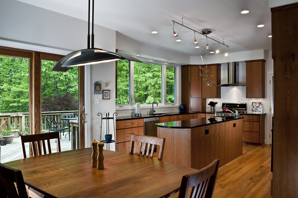 Cette image montre une cuisine américaine parallèle design en bois brun de taille moyenne avec un placard à porte plane, un électroménager en acier inoxydable, un sol en bois brun et îlot.