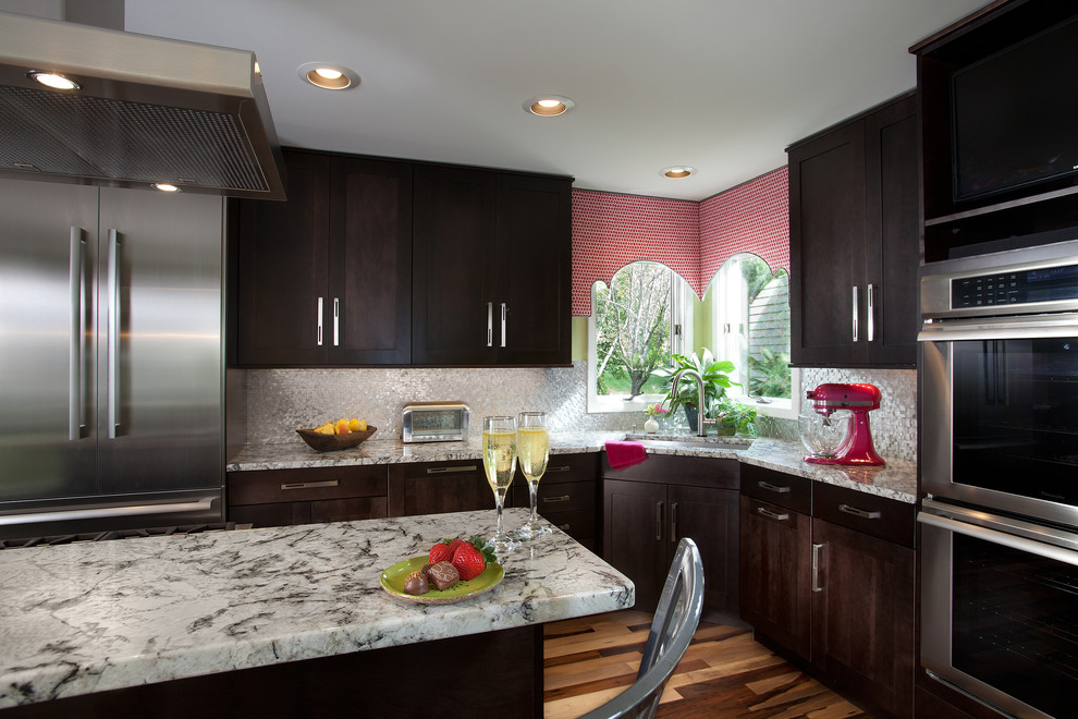 Example of a mid-sized transitional l-shaped medium tone wood floor eat-in kitchen design in Other with an undermount sink, shaker cabinets, dark wood cabinets, granite countertops, metallic backsplash, metal backsplash, stainless steel appliances and an island