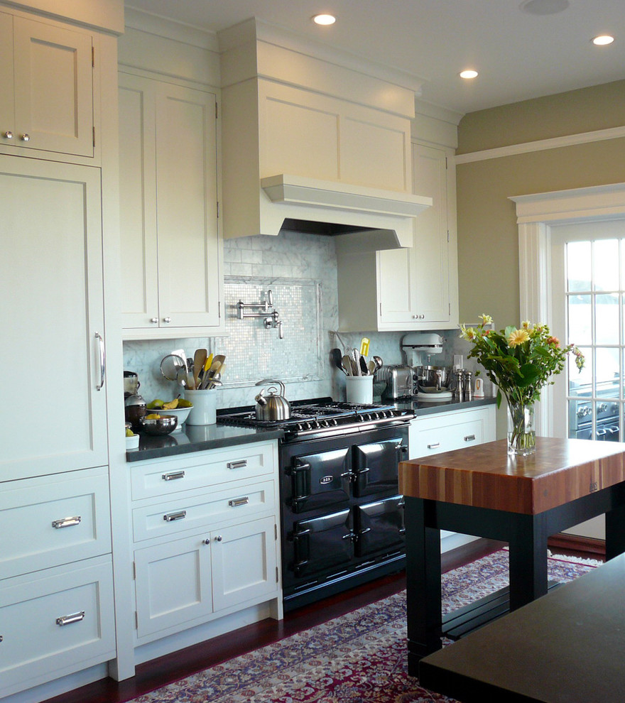 This is an example of a traditional kitchen in San Francisco with shaker cabinets, white cabinets, white splashback, stone tiled splashback, black appliances and engineered stone countertops.