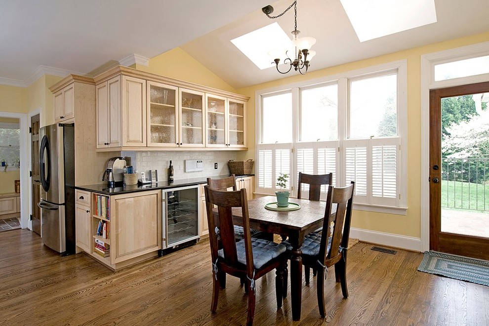 Klassisk inredning av ett kök, med luckor med upphöjd panel, skåp i ljust trä, vitt stänkskydd, stänkskydd i tunnelbanekakel och rostfria vitvaror