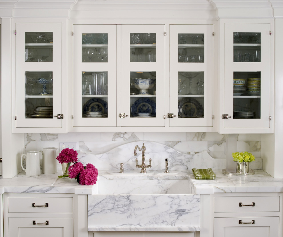 Diseño de cocina clásica con fregadero sobremueble, armarios tipo vitrina, puertas de armario blancas y salpicadero blanco