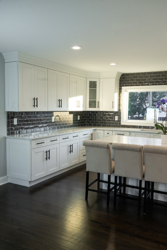 Inspiration for a large modern u-shaped dark wood floor and brown floor eat-in kitchen remodel in Newark with shaker cabinets, white cabinets, gray backsplash, subway tile backsplash, stainless steel appliances and an island