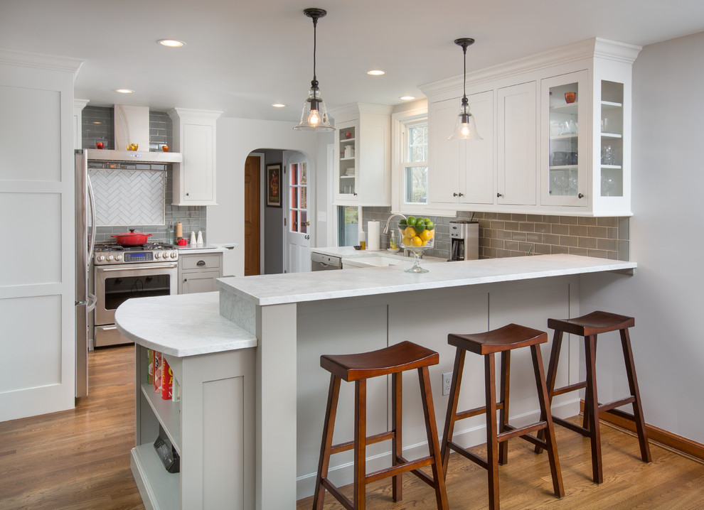 Inspiration for a transitional medium tone wood floor kitchen remodel in Columbus with shaker cabinets, white cabinets, gray backsplash, subway tile backsplash, stainless steel appliances and a peninsula