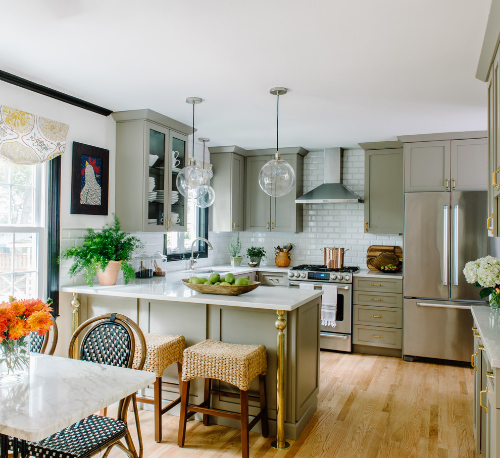 Example of a mid-sized eclectic u-shaped light wood floor enclosed kitchen design in Austin with an undermount sink, shaker cabinets, gray cabinets, quartz countertops, white backsplash, subway tile backsplash, stainless steel appliances and a peninsula