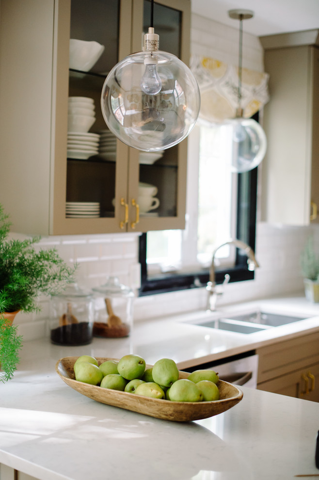 Bild på ett litet eklektiskt kök, med en dubbel diskho, luckor med glaspanel, beige skåp, laminatbänkskiva, vitt stänkskydd, stänkskydd i tunnelbanekakel, rostfria vitvaror och en halv köksö