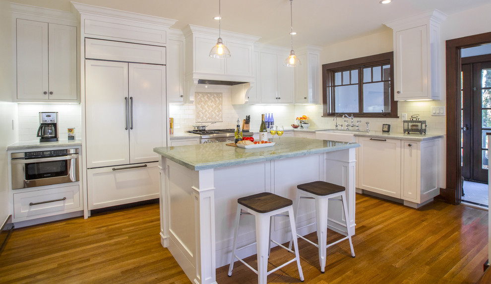 This is an example of a large traditional kitchen/diner in Los Angeles with an island, shaker cabinets, white cabinets, quartz worktops, white splashback, metro tiled splashback, stainless steel appliances, a belfast sink and medium hardwood flooring.