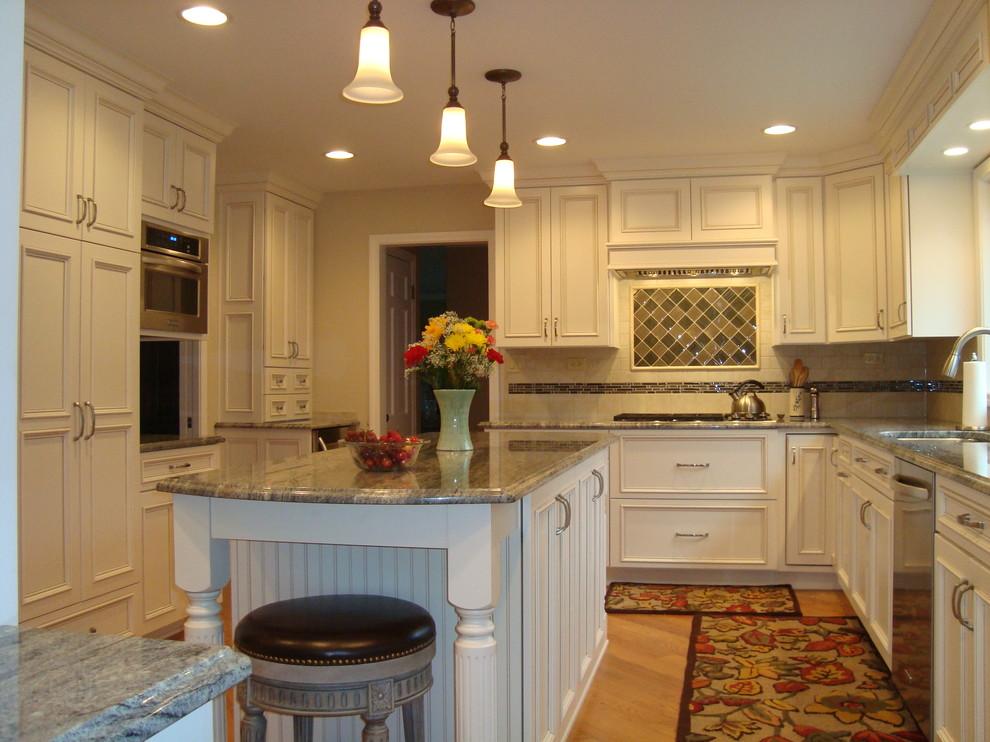 Example of a large classic l-shaped light wood floor enclosed kitchen design in Chicago with a double-bowl sink, recessed-panel cabinets, white cabinets, marble countertops, multicolored backsplash, glass tile backsplash, stainless steel appliances and an island
