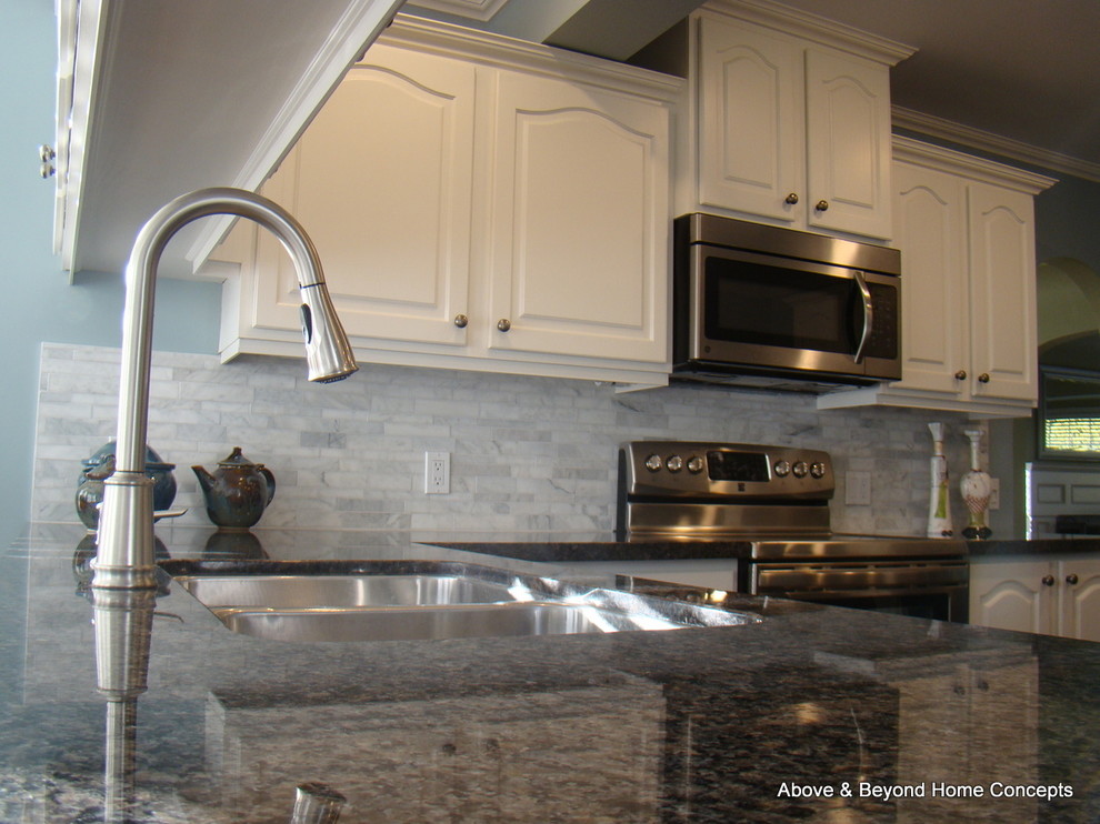 Example of a transitional u-shaped eat-in kitchen design in Vancouver with an undermount sink, raised-panel cabinets, white cabinets, granite countertops, white backsplash, stone tile backsplash and stainless steel appliances