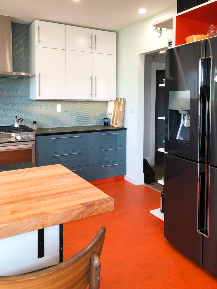This is an example of a medium sized modern u-shaped kitchen pantry in Los Angeles with flat-panel cabinets, white cabinets, blue splashback, stainless steel appliances, a breakfast bar, orange floors, a built-in sink, granite worktops, mosaic tiled splashback, black worktops and vinyl flooring.
