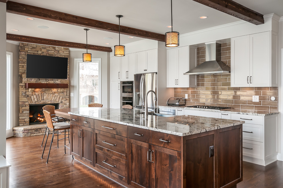 Elegant dark wood floor and brown floor kitchen photo in Atlanta with shaker cabinets, white cabinets, brown backsplash, subway tile backsplash, stainless steel appliances and an island