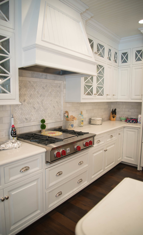 Inredning av ett kök, med en undermonterad diskho, skåp i rostfritt stål, bänkskiva i kvarts, vitt stänkskydd, stänkskydd i stenkakel och en köksö