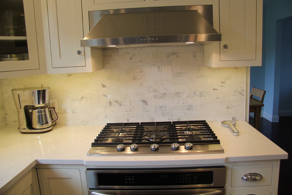 Exempel på ett klassiskt kök, med skåp i shakerstil, vita skåp, marmorbänkskiva, vitt stänkskydd, stänkskydd i tunnelbanekakel, rostfria vitvaror och en köksö