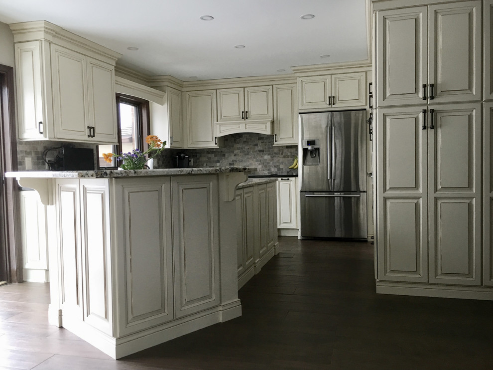 Large elegant u-shaped dark wood floor and brown floor kitchen photo in Other with an undermount sink, raised-panel cabinets, white cabinets, granite countertops, multicolored backsplash, terra-cotta backsplash, stainless steel appliances, an island and black countertops
